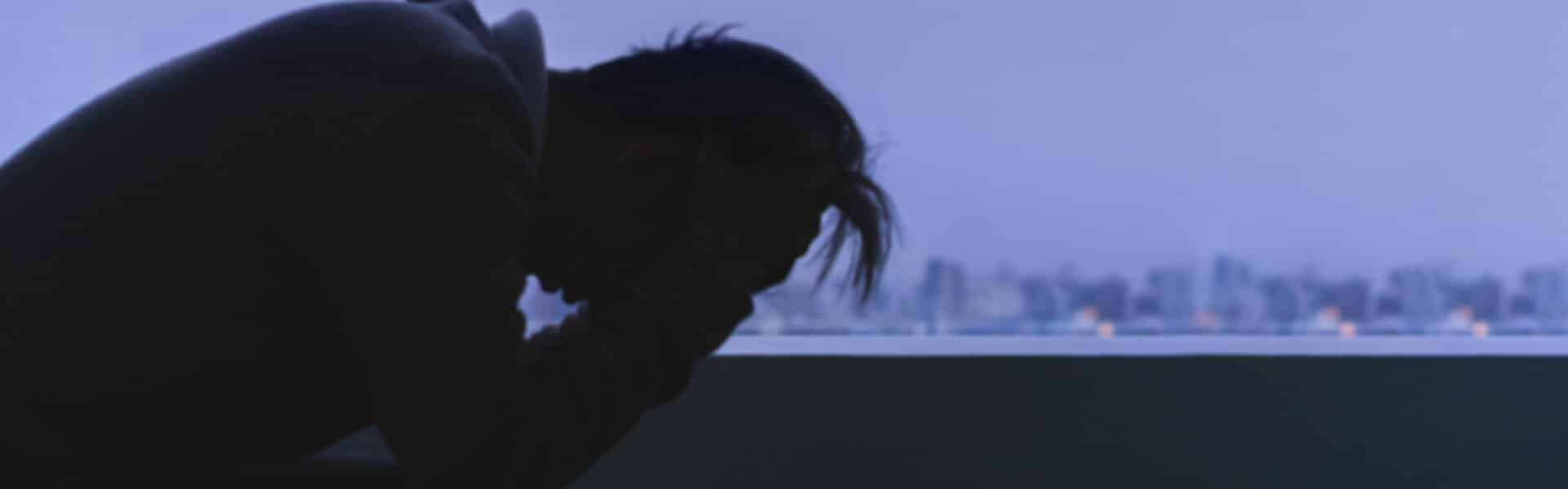 Stressed person crouched down and holding head.