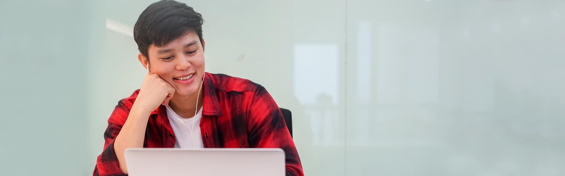 young man on laptop using earbuds