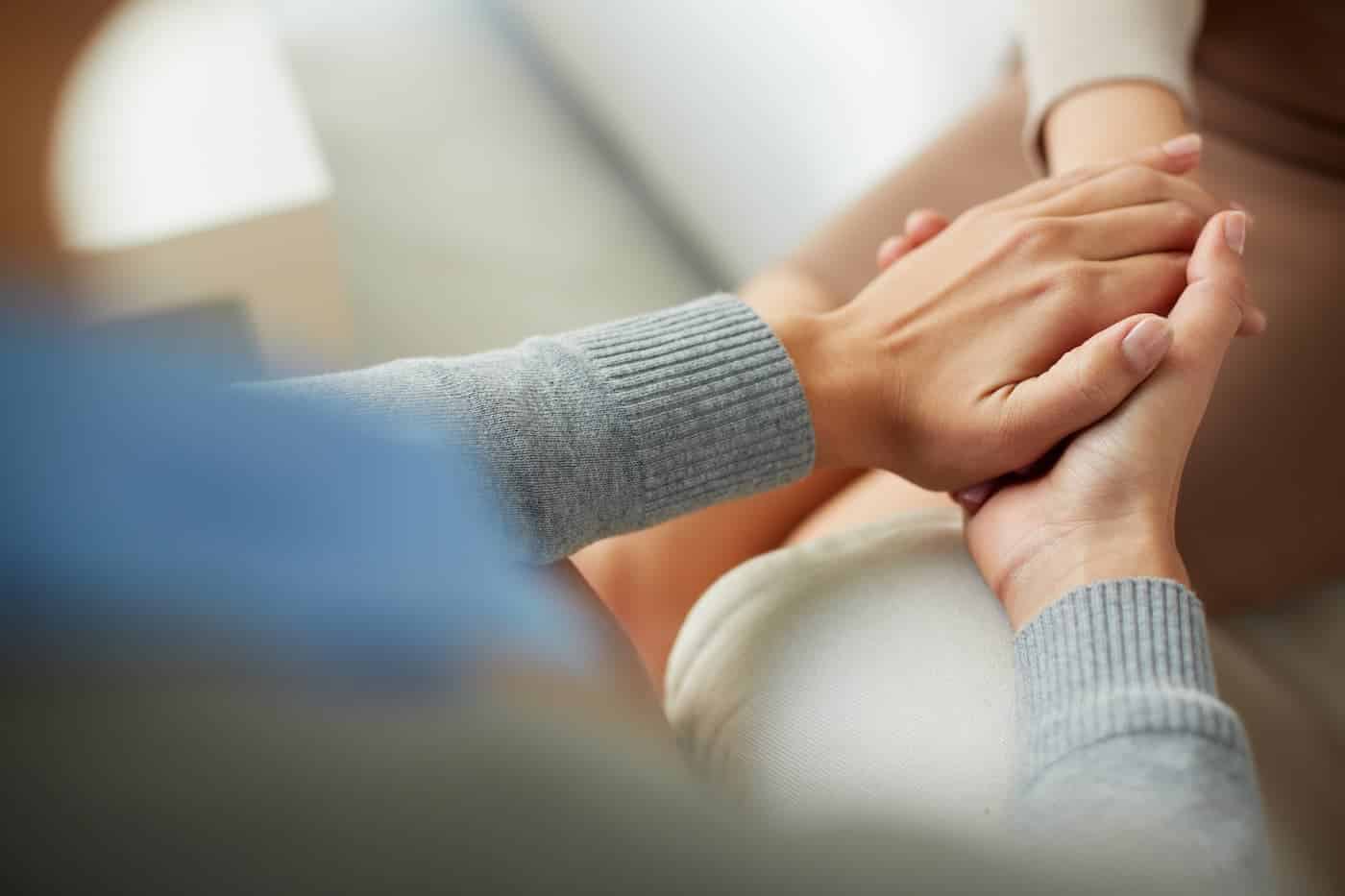 Close-up of psychiatrist hands together holding palm of her patient.